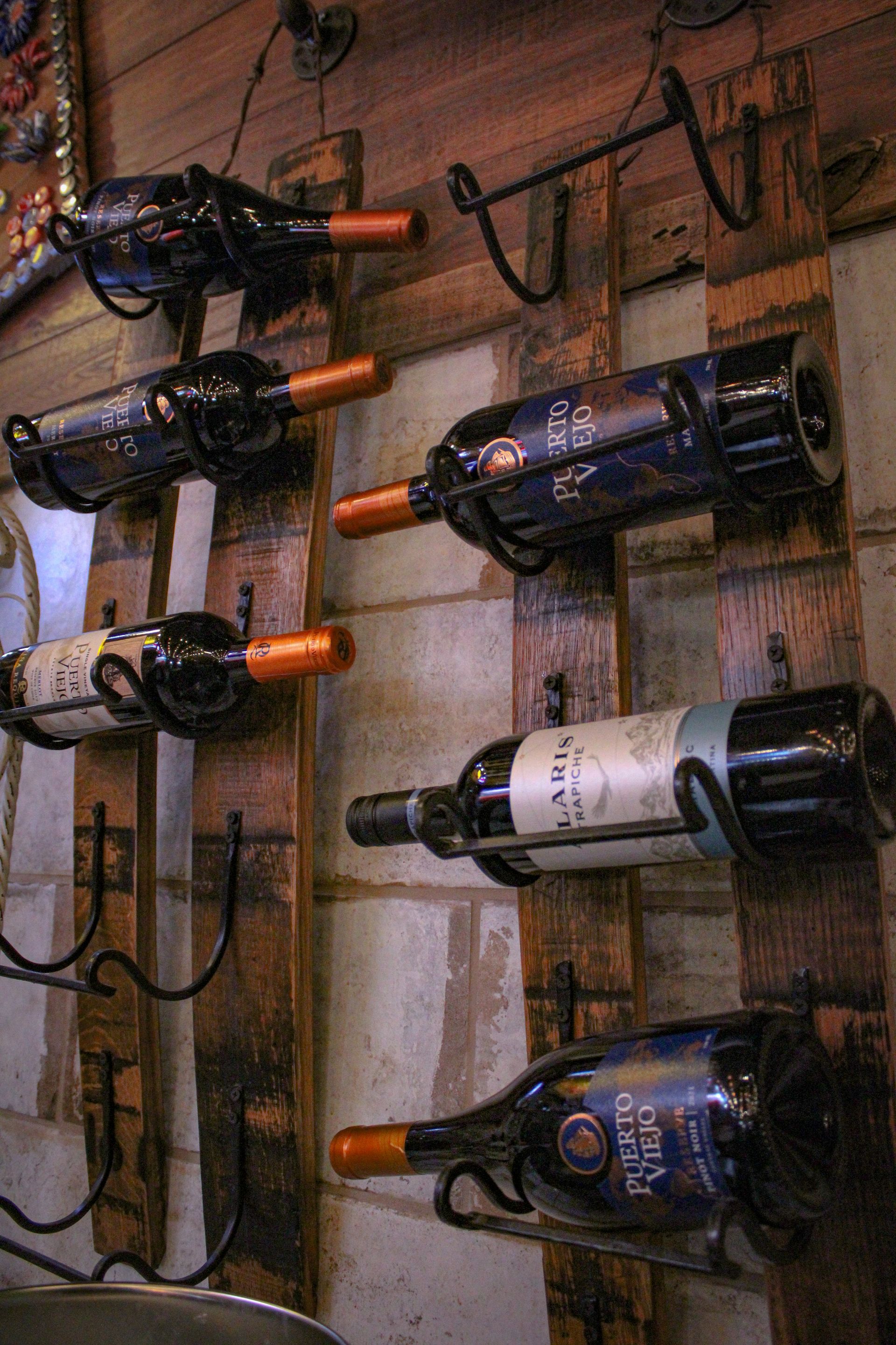A row of wine bottles hanging on a wooden rack.