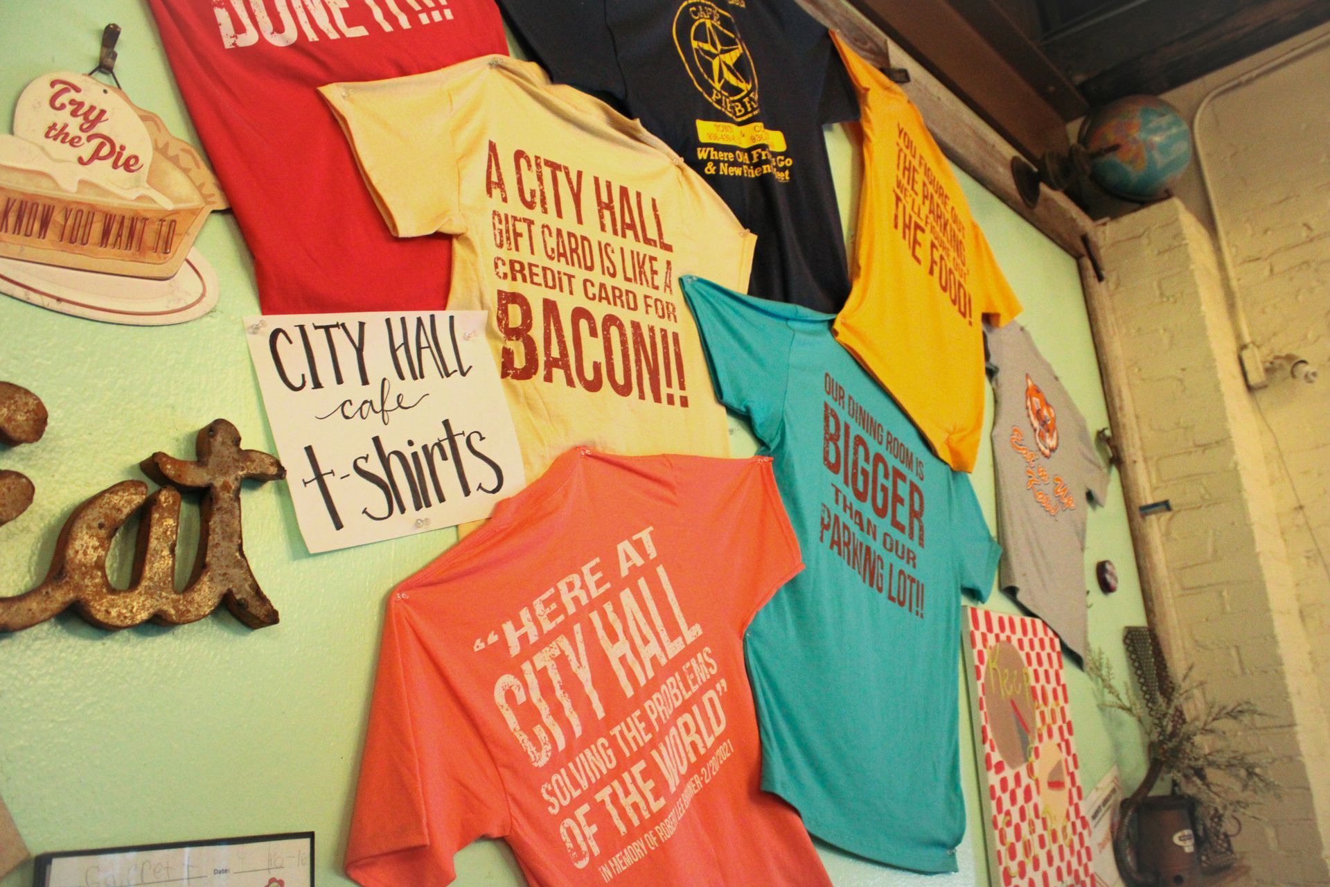 A bunch of t-shirts hanging on a wall including one that says 