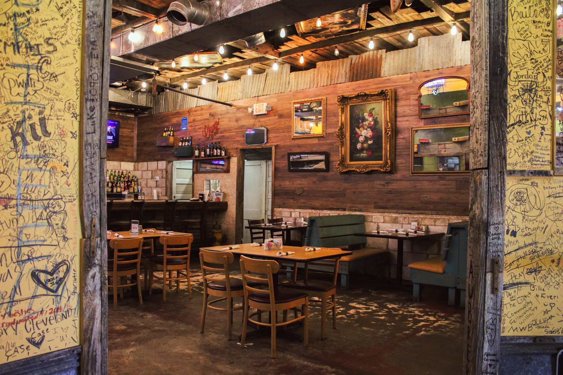 A restaurant with tables and chairs and graffiti on the walls.