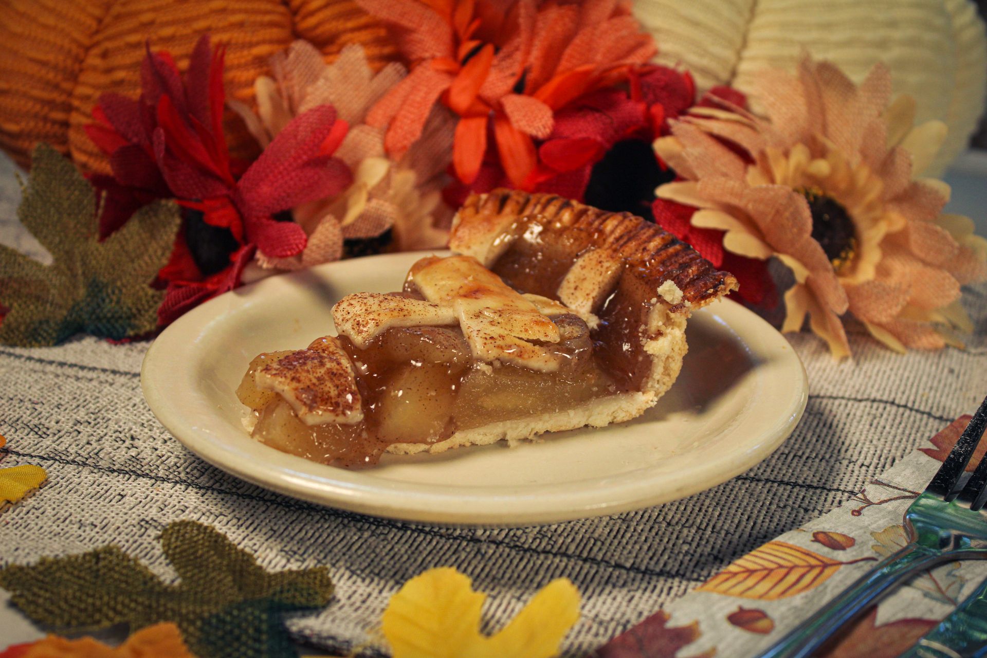 A slice of apple pie is on a white plate on a table.