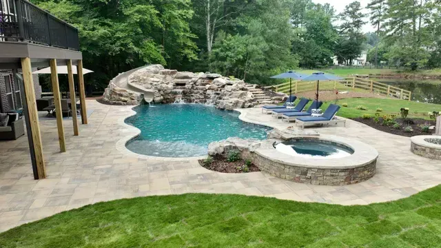 Backyard with pool and spa, waterfall, deck, and lake view.