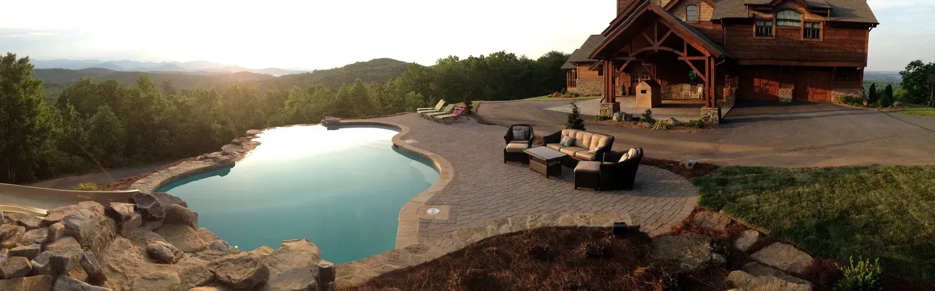 A luxury cabin with a pool overlooking a lush, green landscape at sunset.
