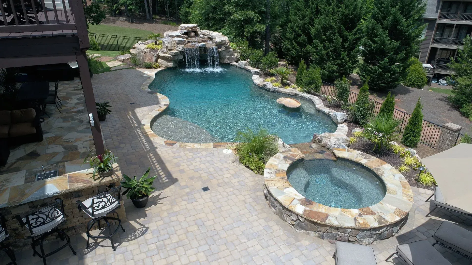 Pool and spa with a waterfall feature surrounded by landscaping and patio.