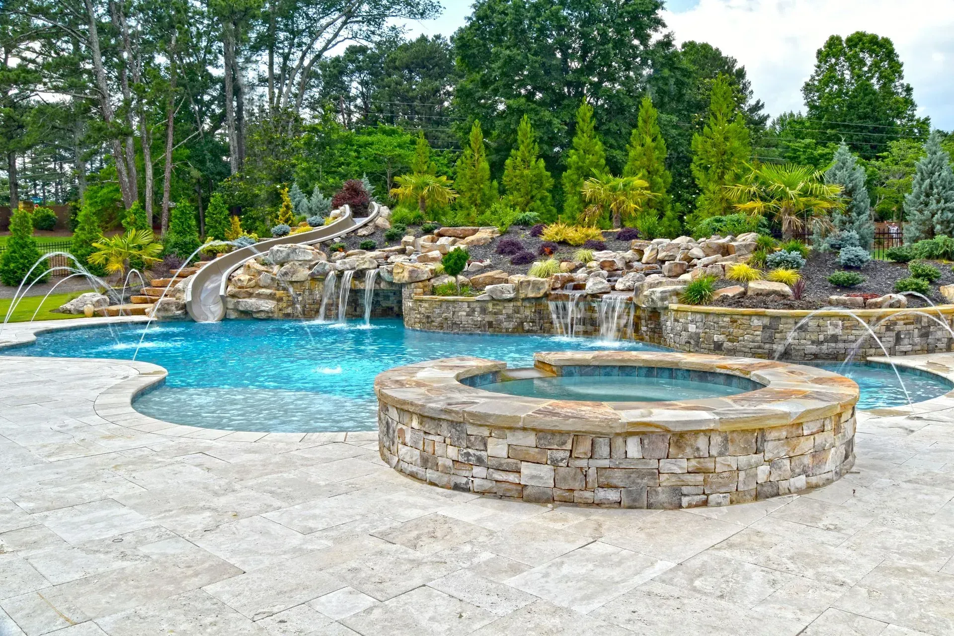 Luxurious backyard pool with a water slide, waterfall features, and a stone hot tub.