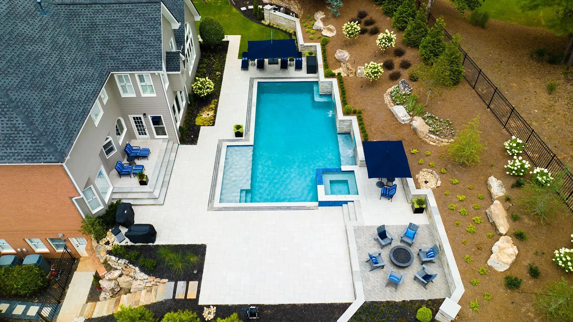 Aerial view of a backyard with a pool, patio, and seating areas. Blue accents throughout.