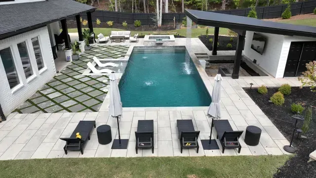 Luxurious backyard with rectangular pool, patio furniture, and modern structures.