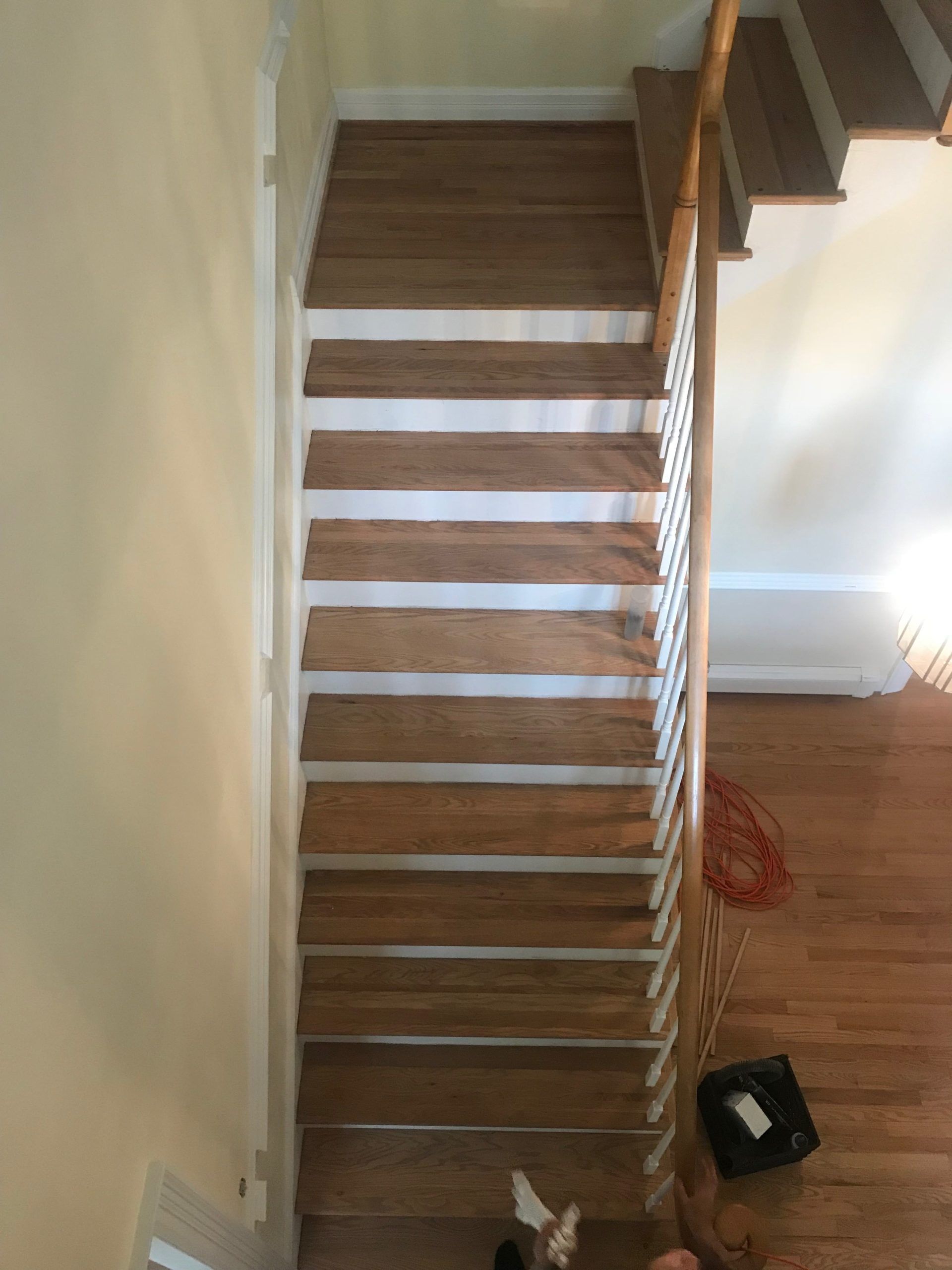 Narrow wooden staircase with white risers in a home interior, viewed from above.