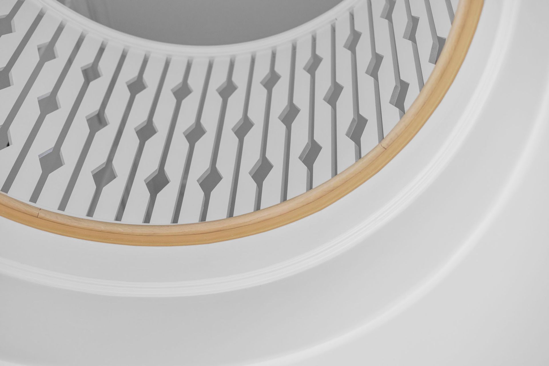 Close-up of a white circular vent with a gold rim and gray geometric pattern inside