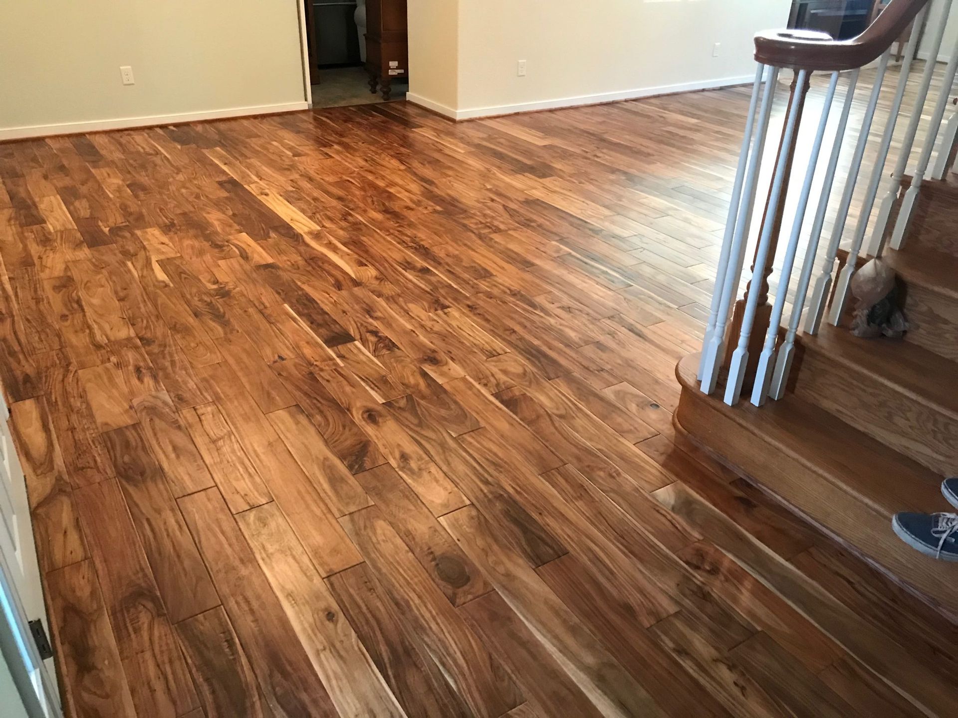 Wooden floor in a home interior with stairs and a doorway in view