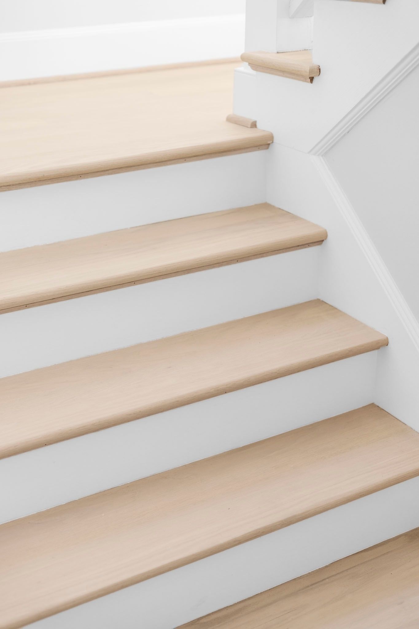Light wood stairs with white risers and a small top landing in a bright interior.