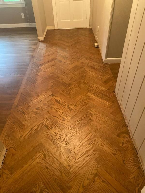 Hallway with herringbone wood floor leading to a closed door