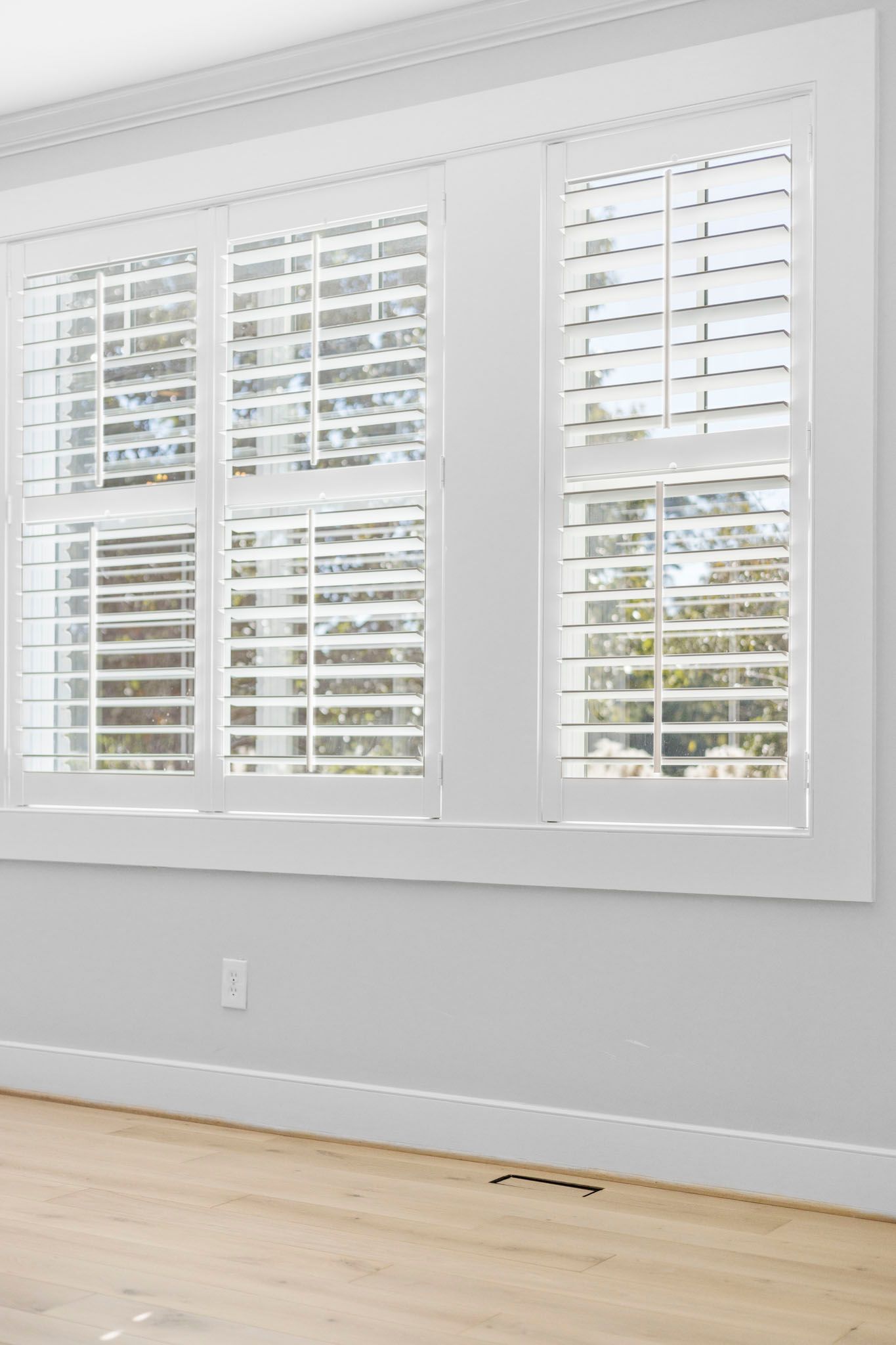 Bright room with white plantation shutters, pale walls, and light wood flooring