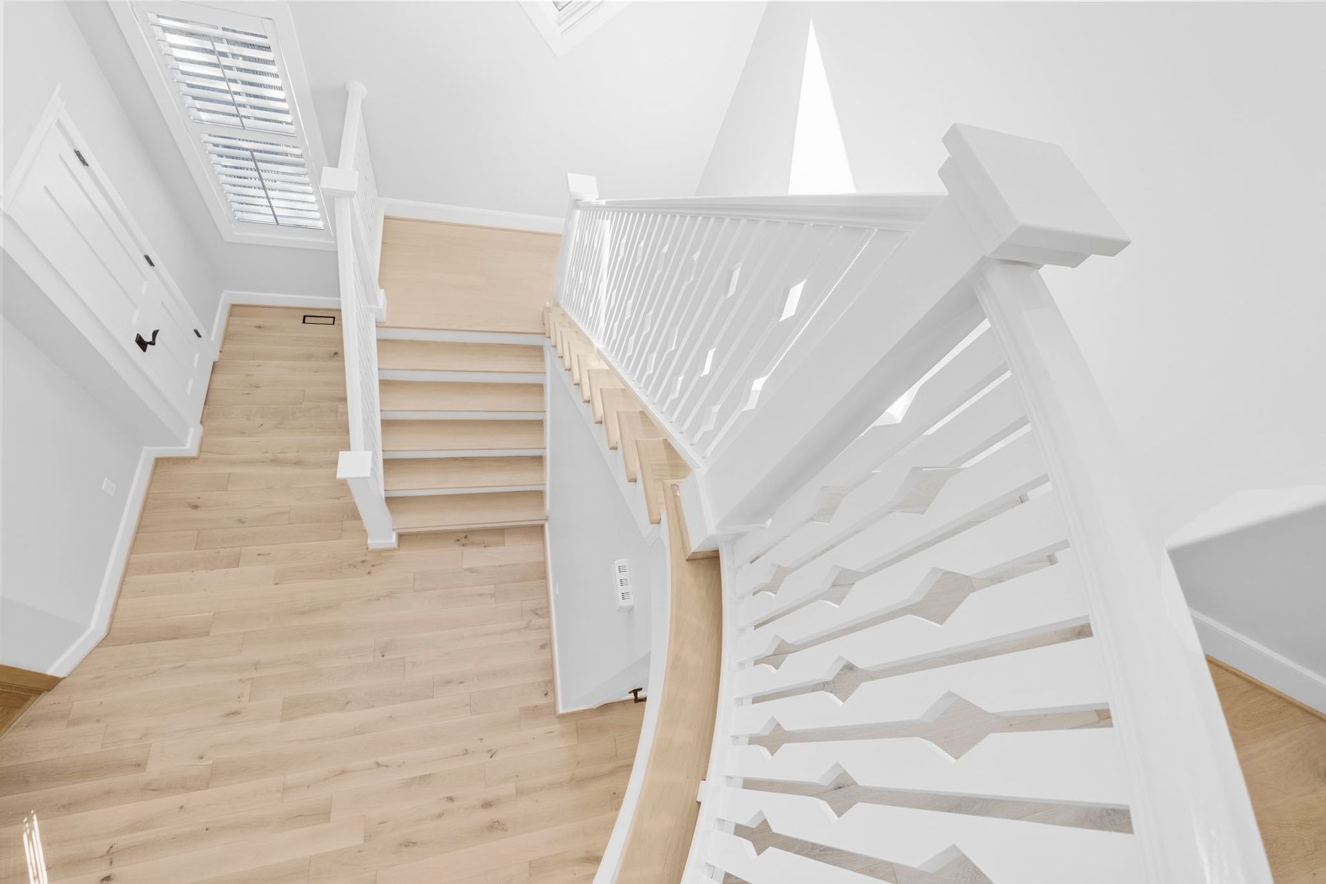 Bright white staircase with light wood steps and curved railing in a modern interior