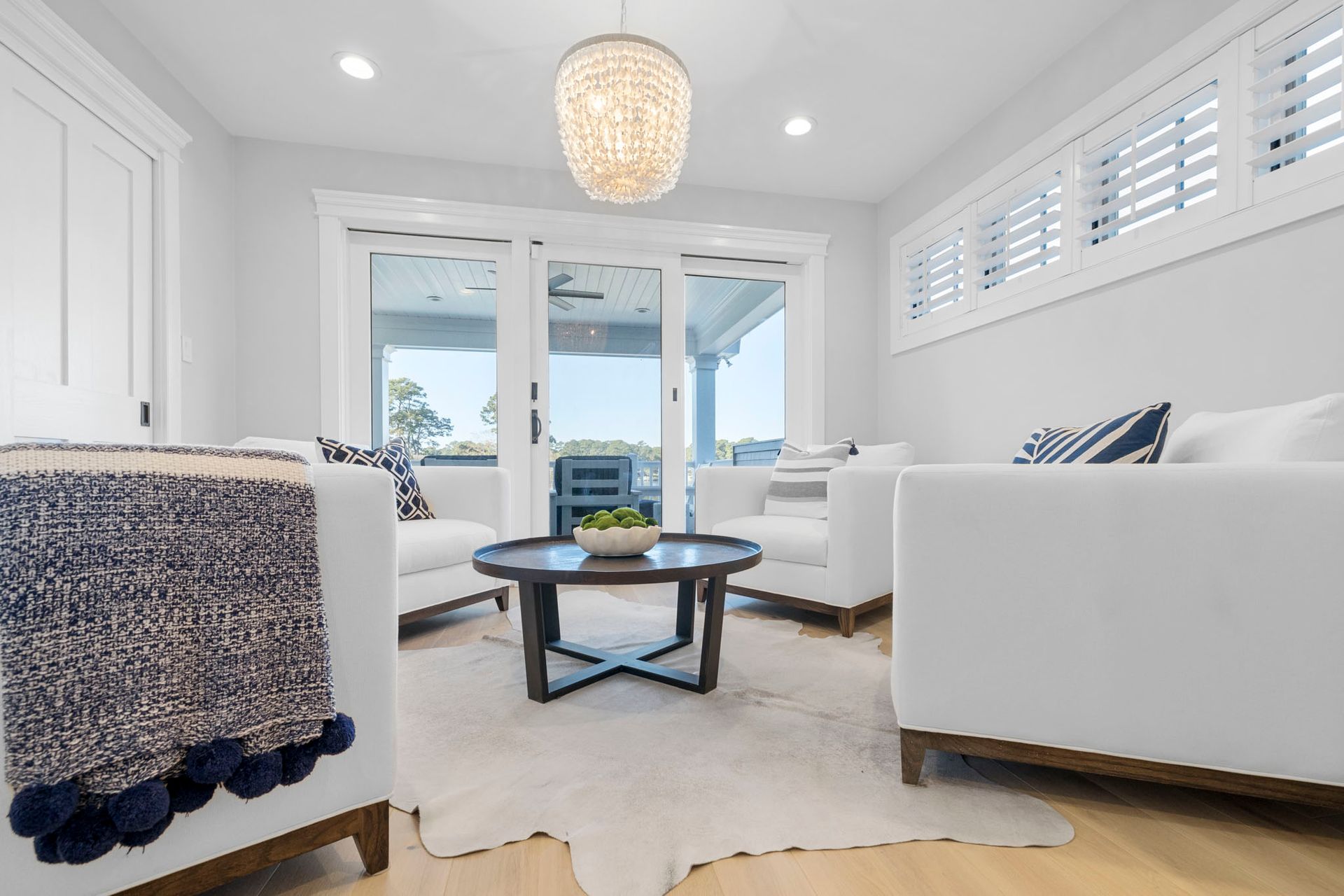 Bright white living room with sofa, coffee table, and glass doors to a sunlit patio