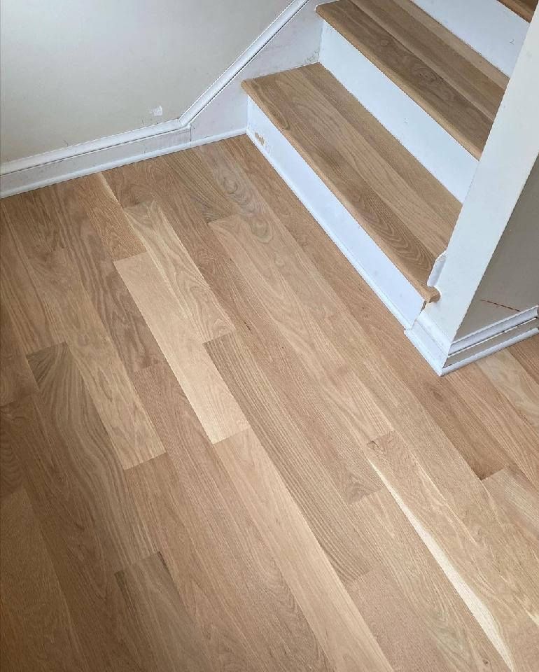 Wooden floor and white stairs with light wood treads in a bright interior.