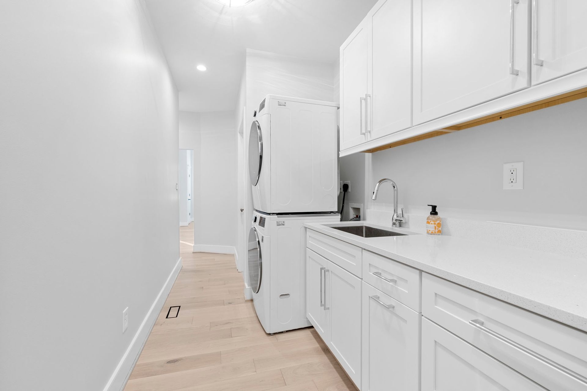 Bright white galley kitchen with refrigerator, sink, and long countertop along the right wall