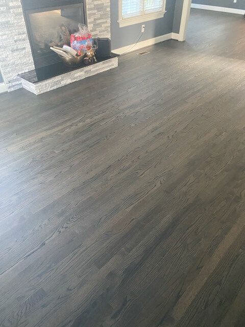 Empty living room with dark wood floors and a fireplace decorated with flowers.