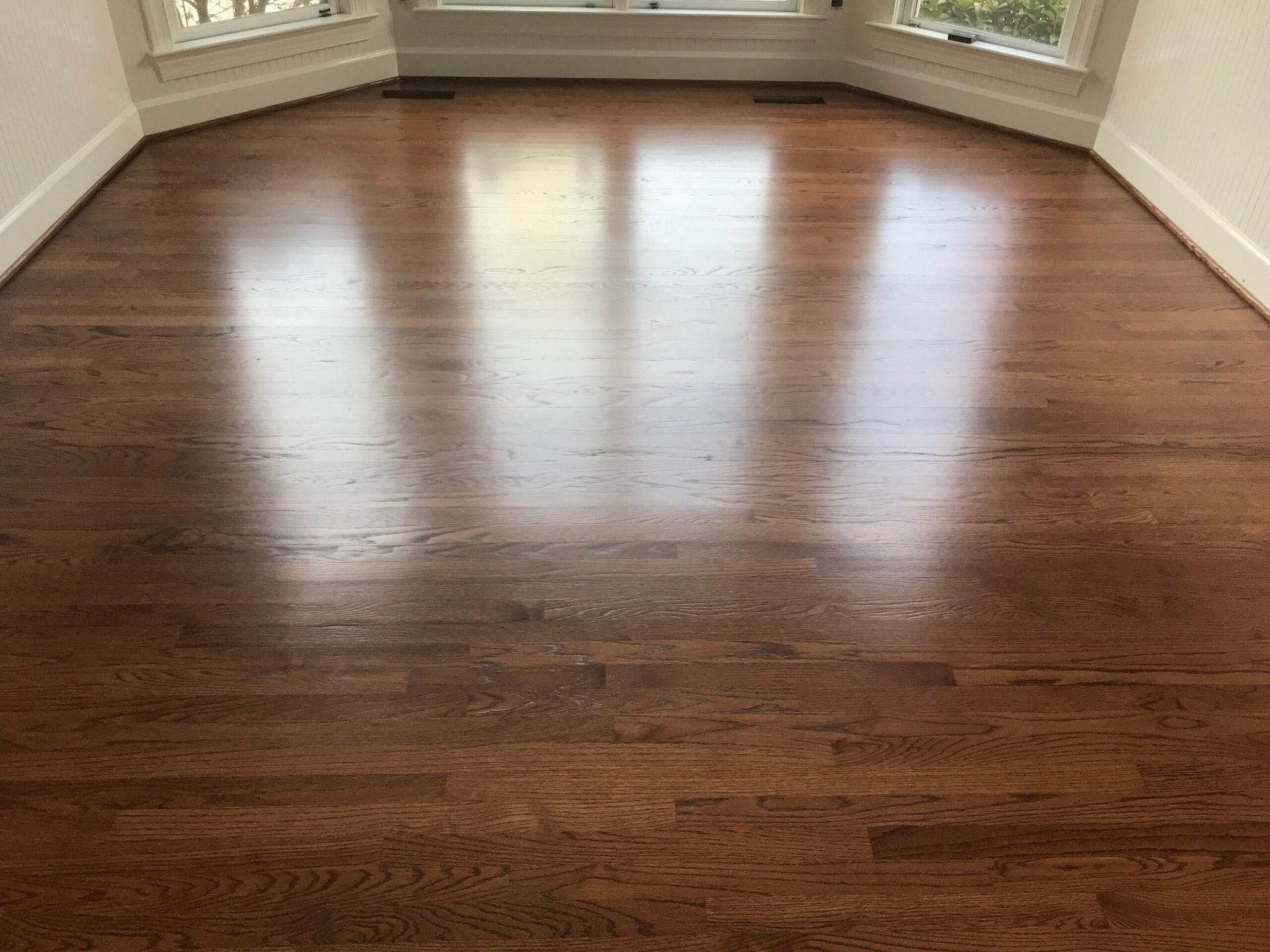 Empty room with polished dark hardwood floors and bay windows letting in natural light