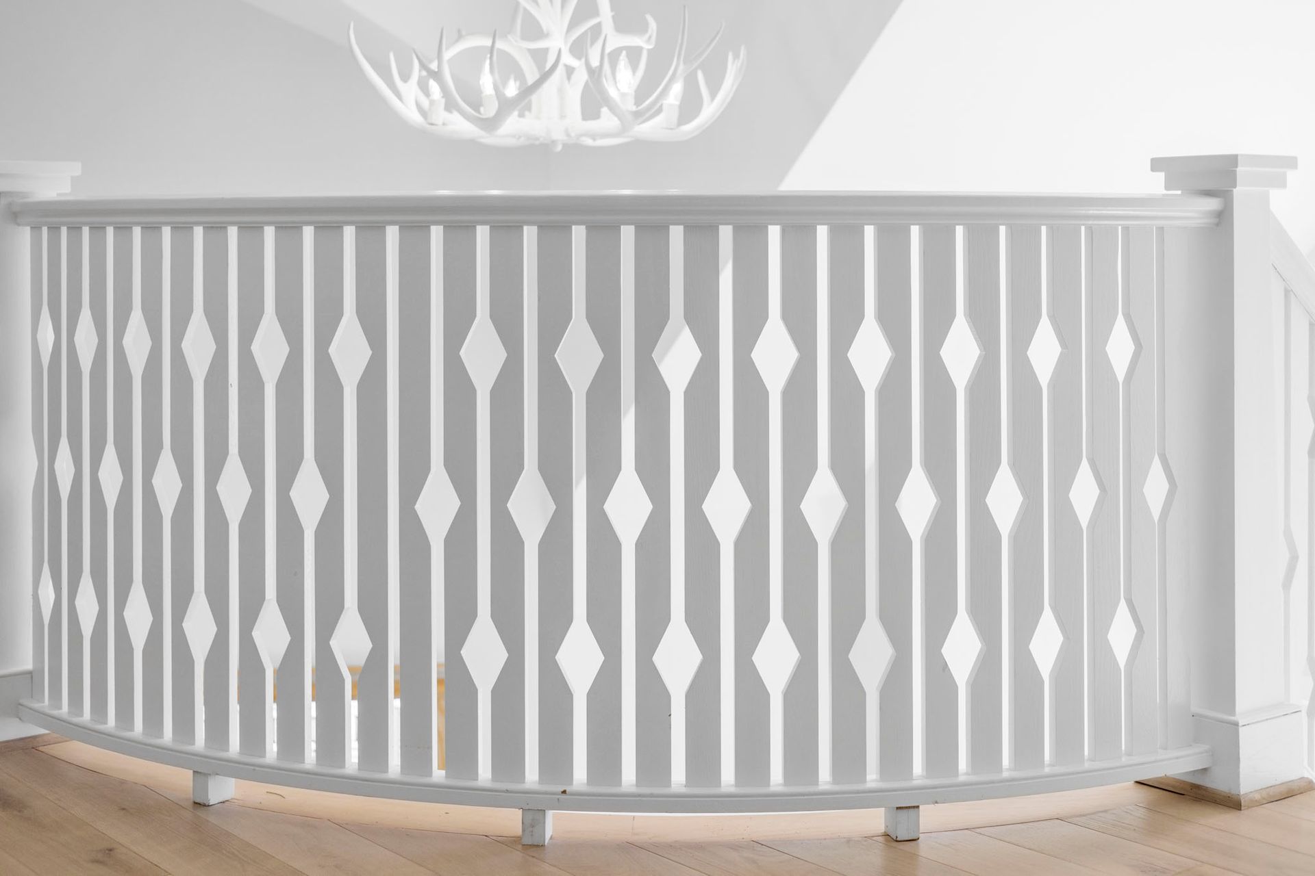 White curved staircase railing with decorative vertical balusters in a bright interior