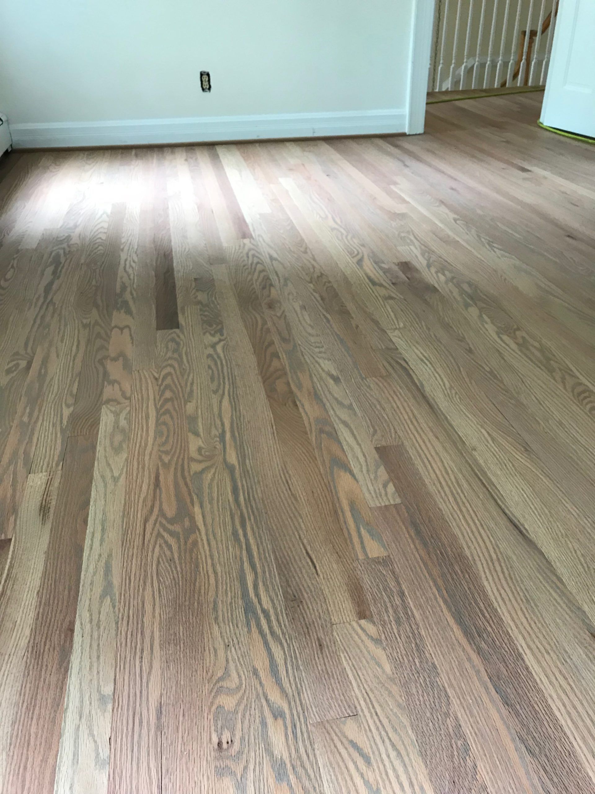 Empty room with light wood flooring, white walls, and a staircase in the back right.