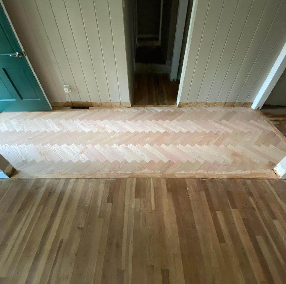 Wooden hallway floor with a light-colored strip and a doorway in the center
