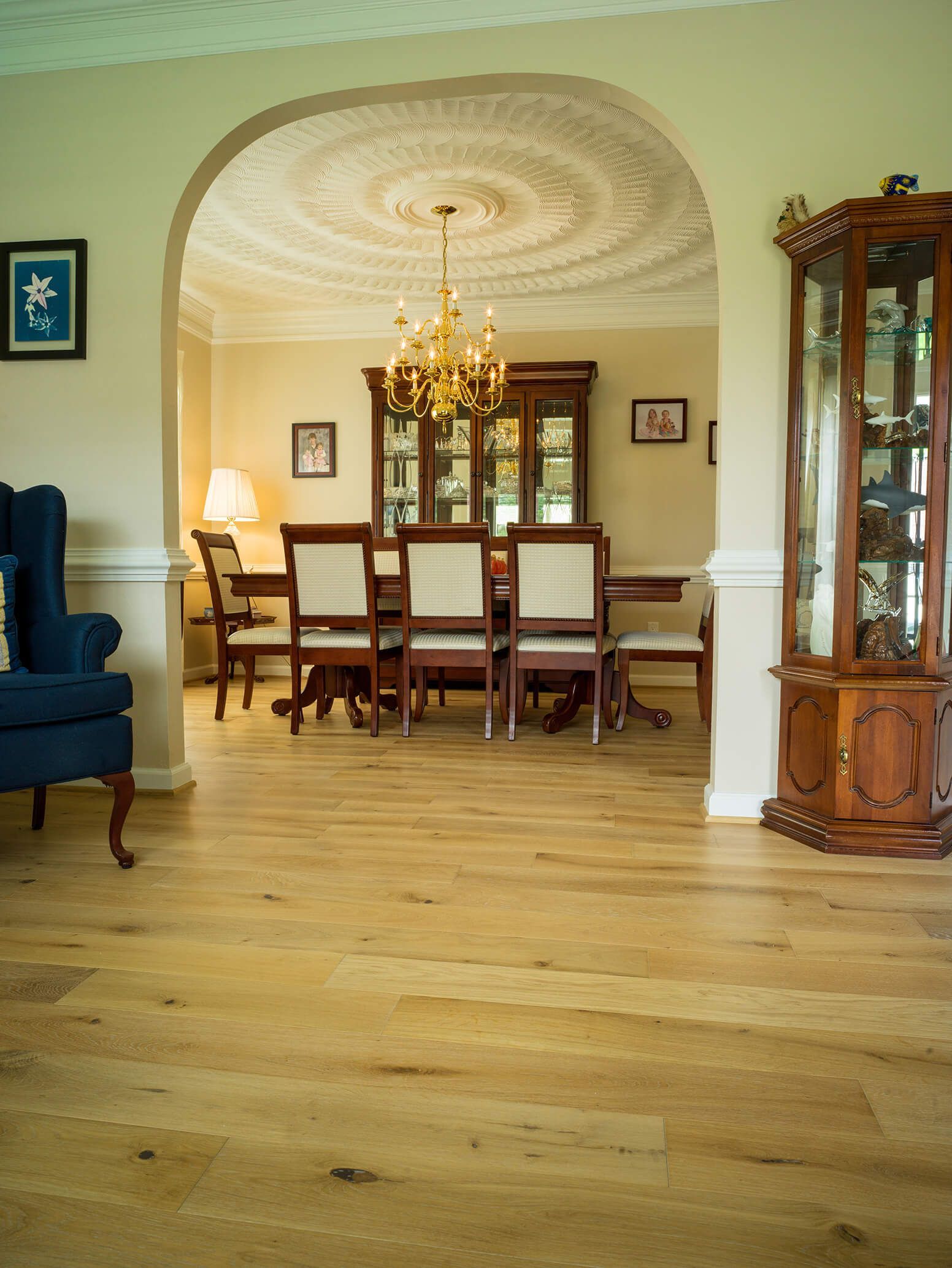 Elegant dining room with chandelier, wooden table and chairs, and polished hardwood floors