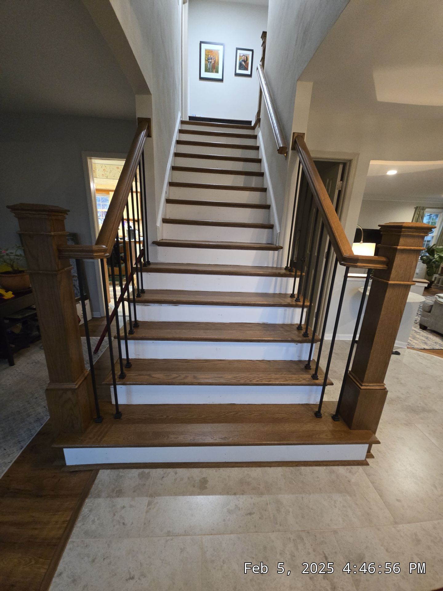 Staircase in a home with wooden railings and white steps, leading up to a hallway.
