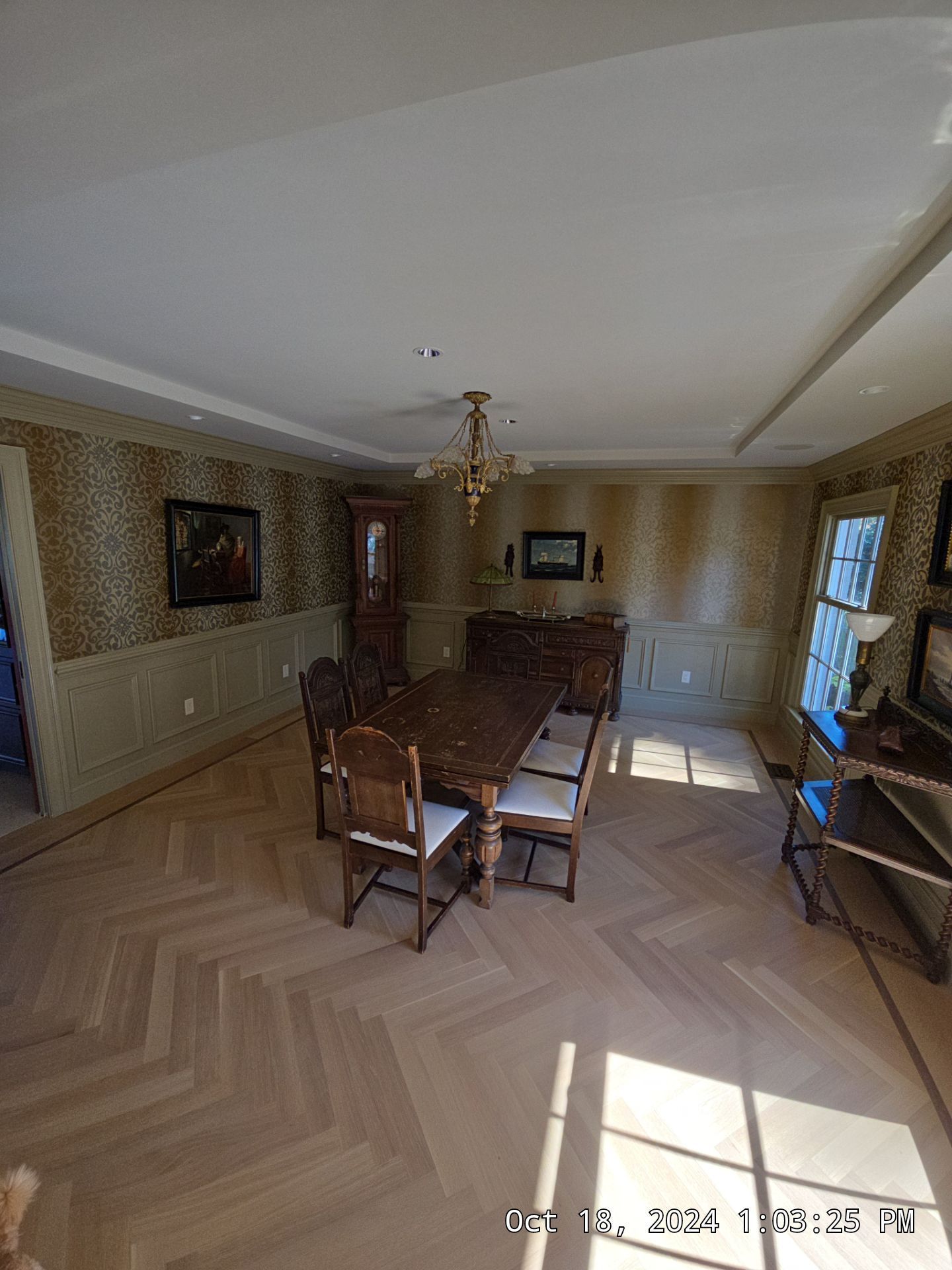 Long dining room with a table, chairs, patterned wallpaper, and sunlight from the right