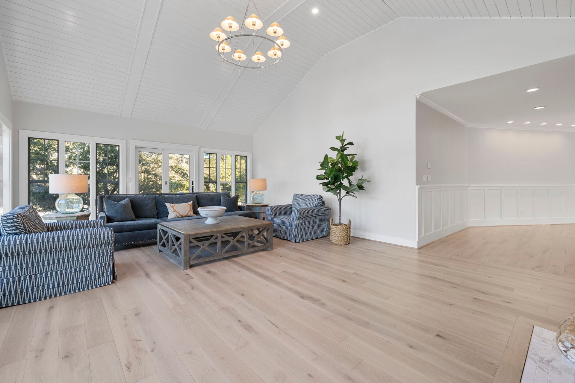 Bright living room with blue sofas, coffee table, white walls, and light wood floors