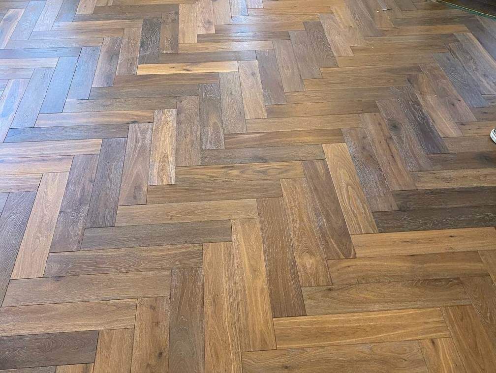 Herringbone-pattern wooden floor with warm brown tones and a glossy finish
