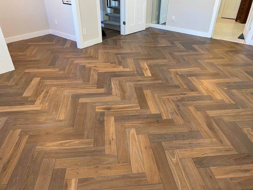 Empty room with herringbone wood-pattern floor and open doorways