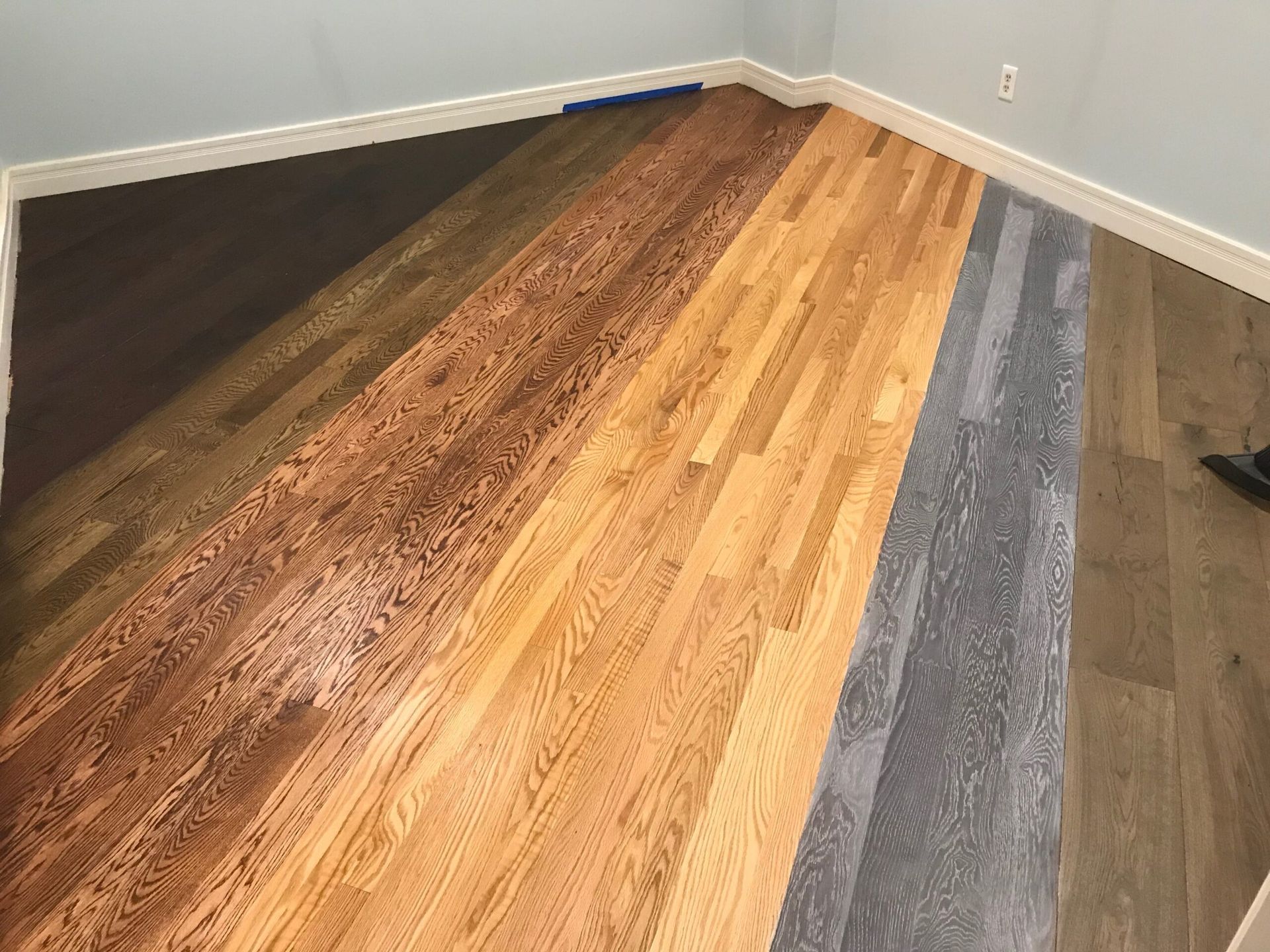 Multi-colored hardwood floor samples laid out in a room against white walls