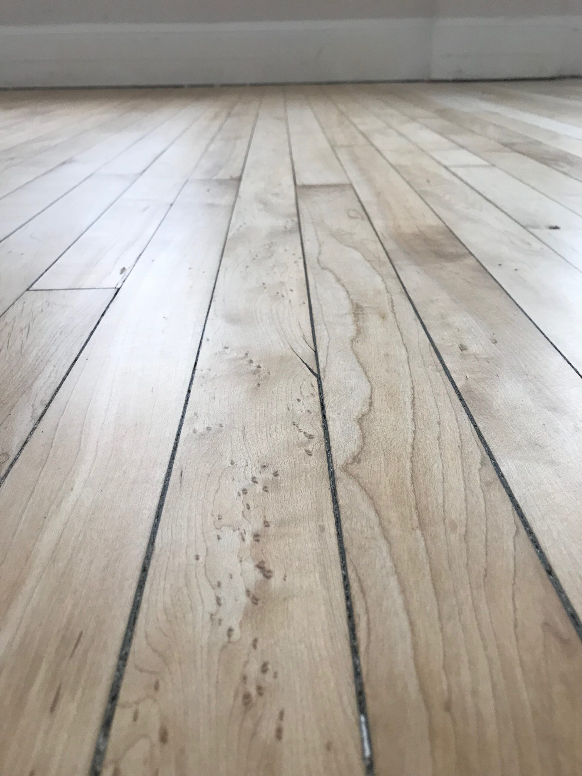 Close-up of a worn wooden floor with visible planks and grain.
