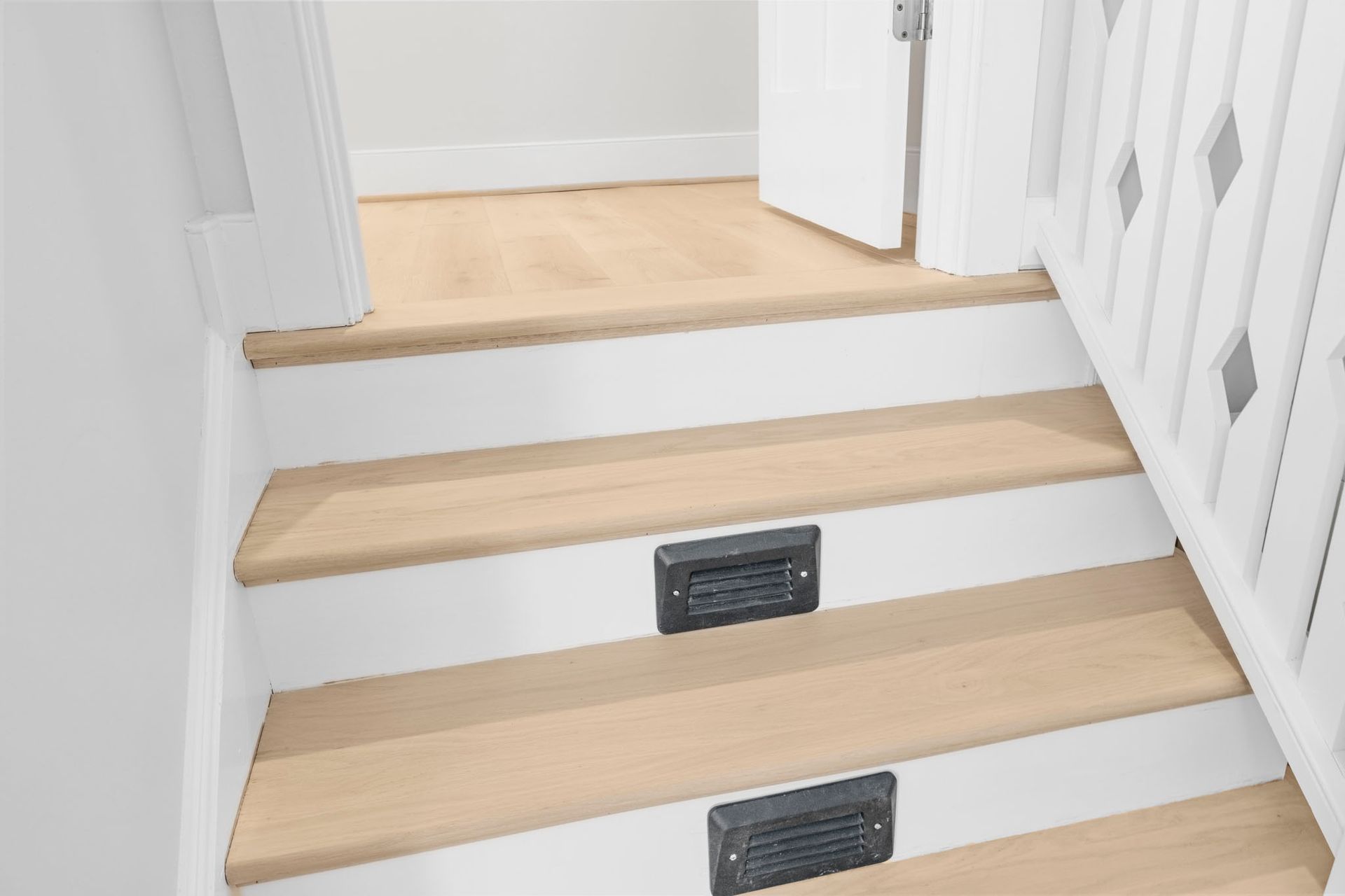 Light wood staircase with white walls and black stair lights leading to an upper landing