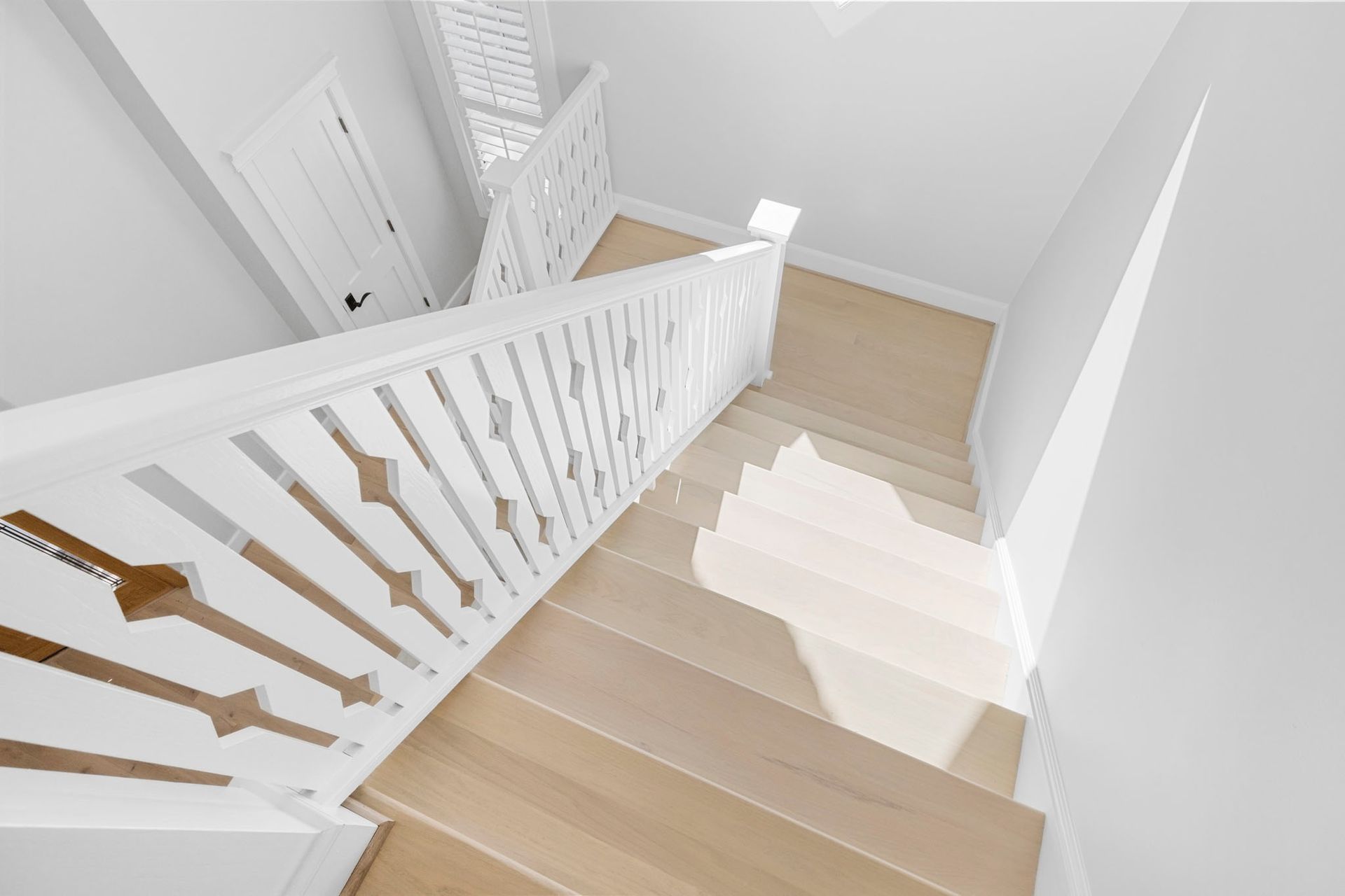Bright white staircase with wooden steps and white railing in a modern interior hallway