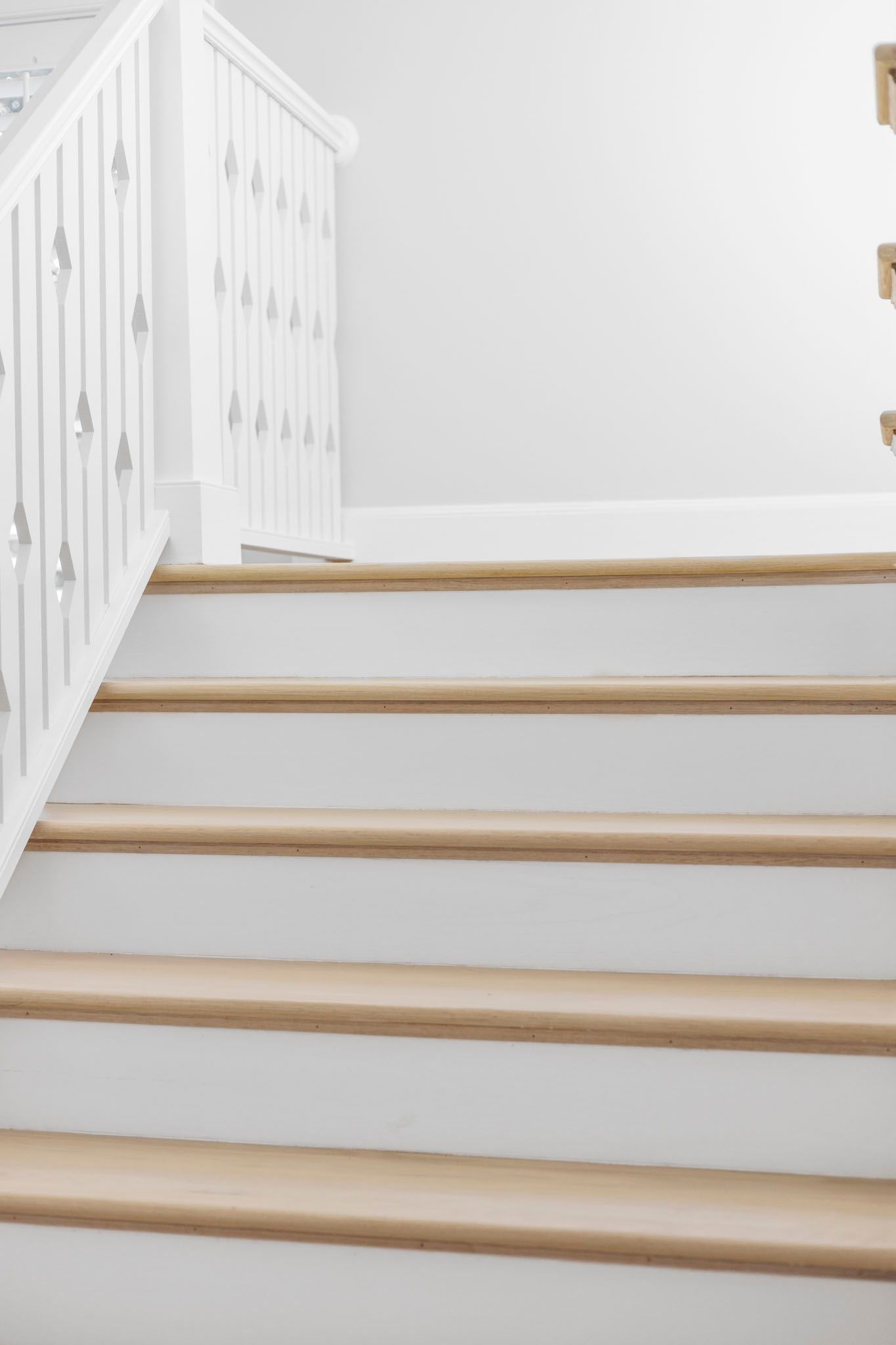 White staircase with wooden treads and a white railing in a bright interior
