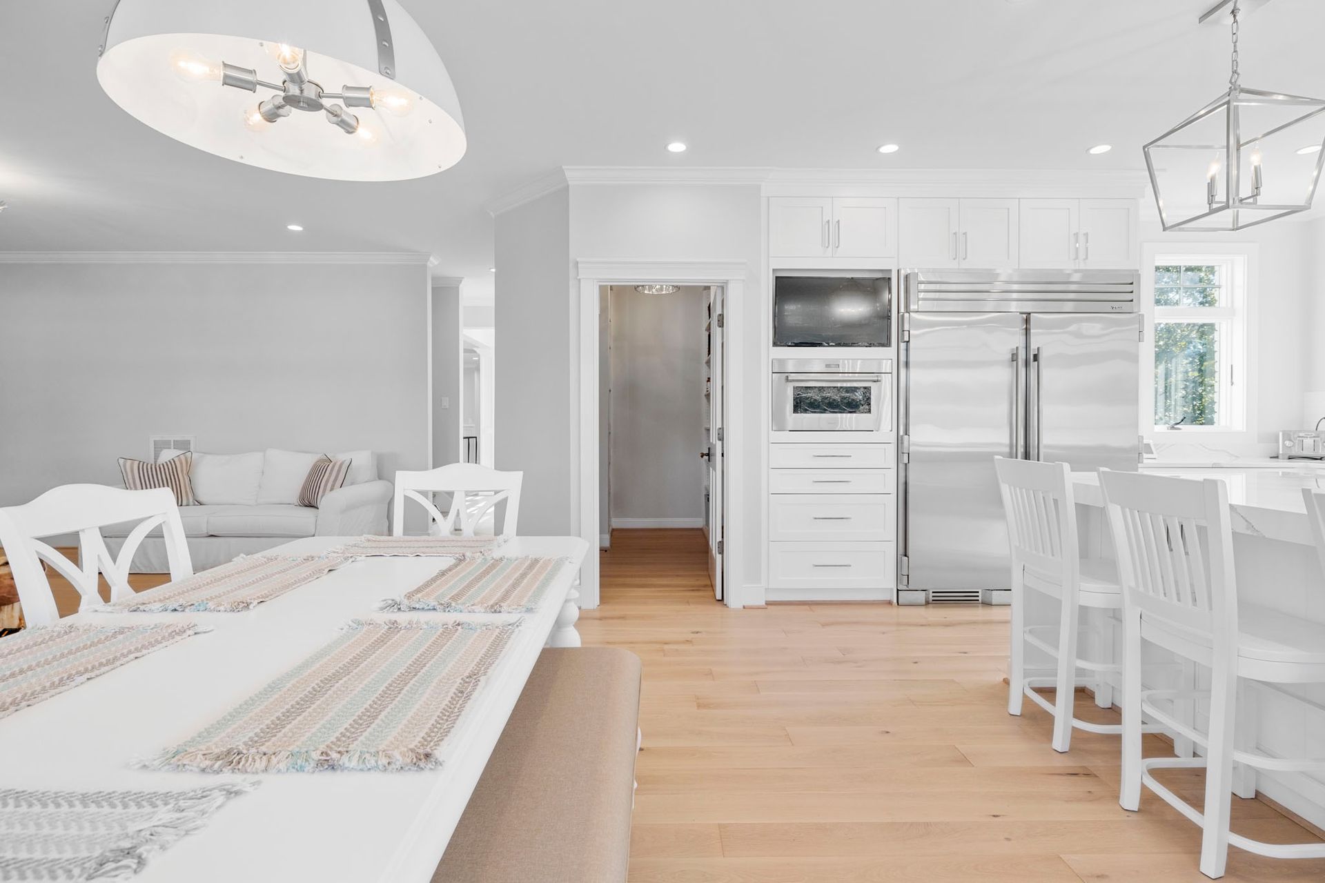 Bright white modern kitchen and dining area with light wood floors and island seating