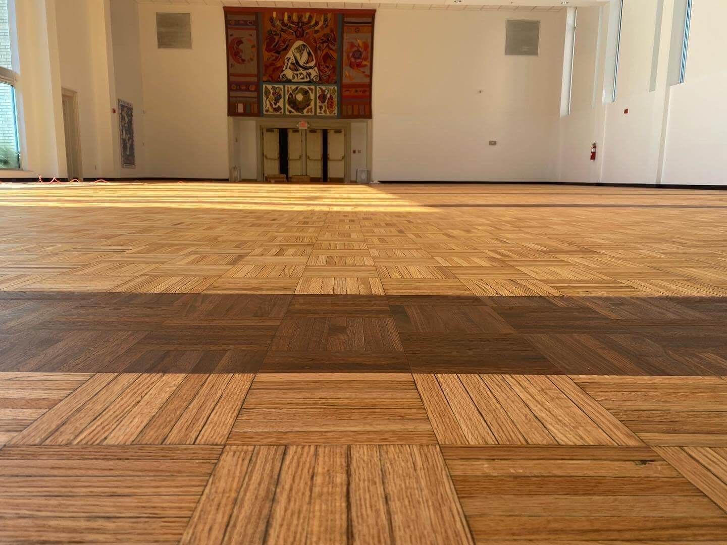 Sunlit wooden floor in an empty room with a decorative altar at the far wall