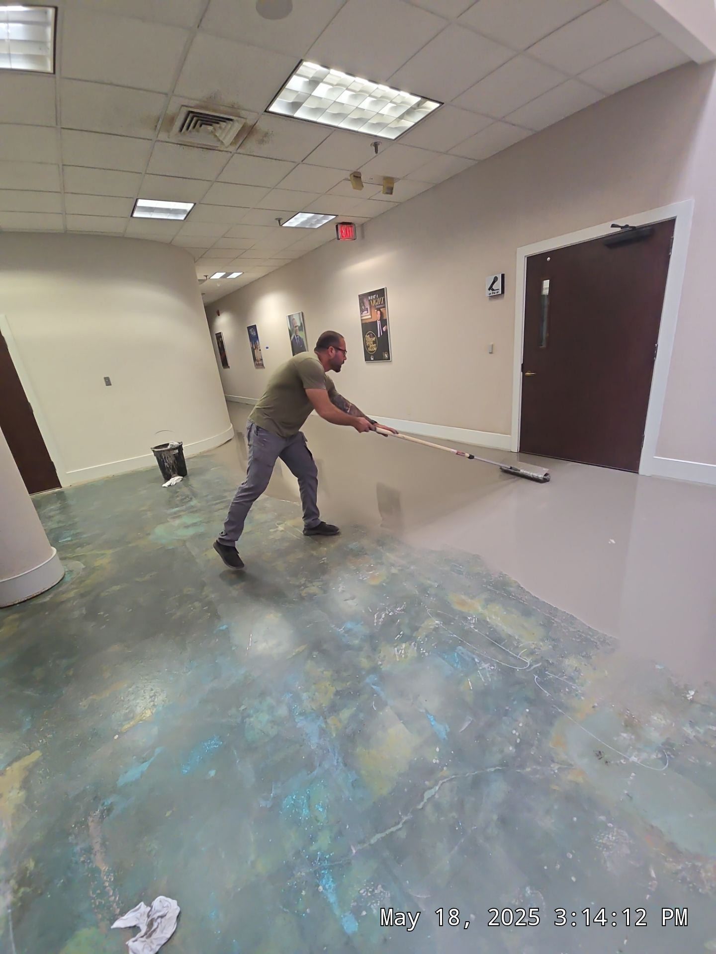Person mopping a hallway floor in a building corridor.