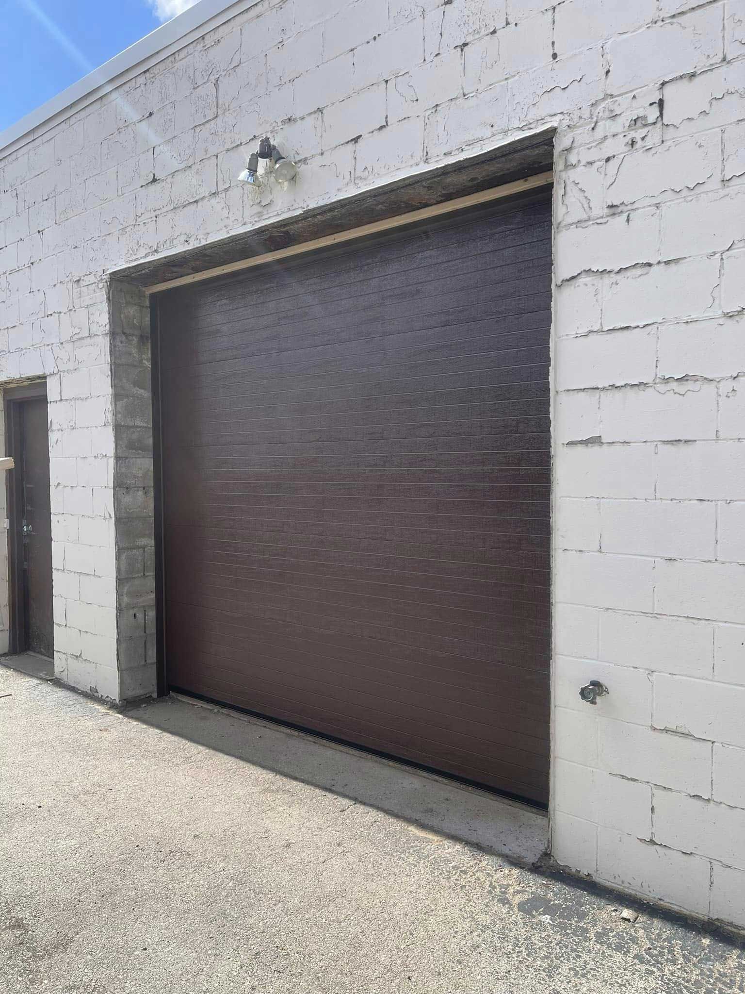 Brown garage door on a white brick building.