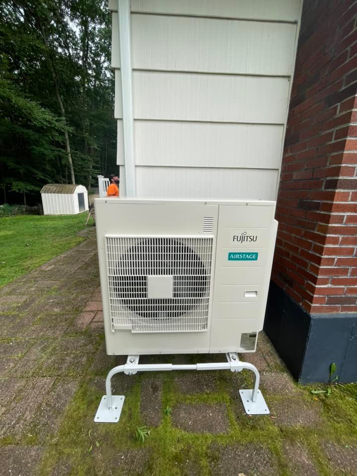 A white air conditioner is sitting outside of a brick building.