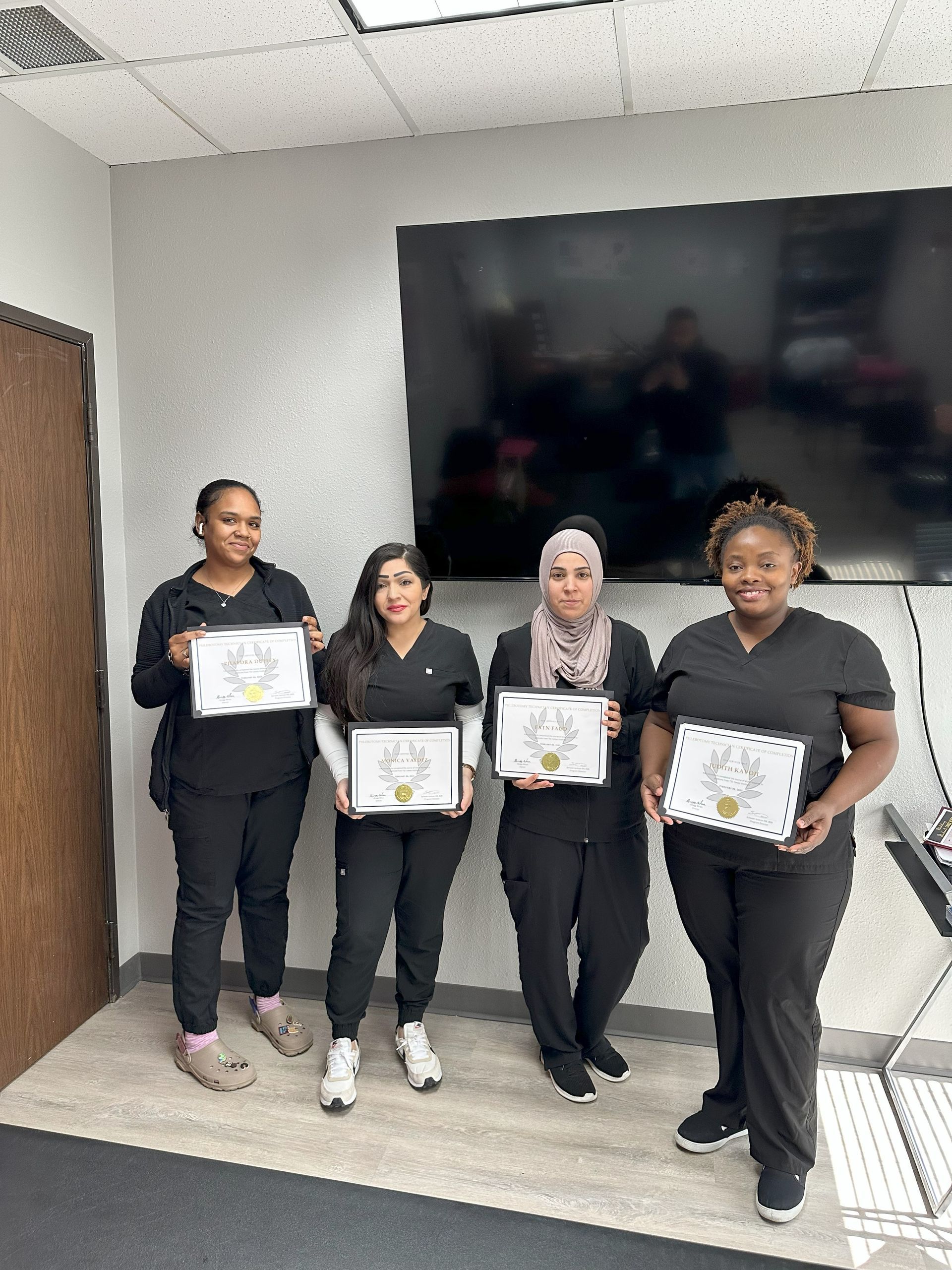 A group of nurses are standing next to each other in a room holding certificates.