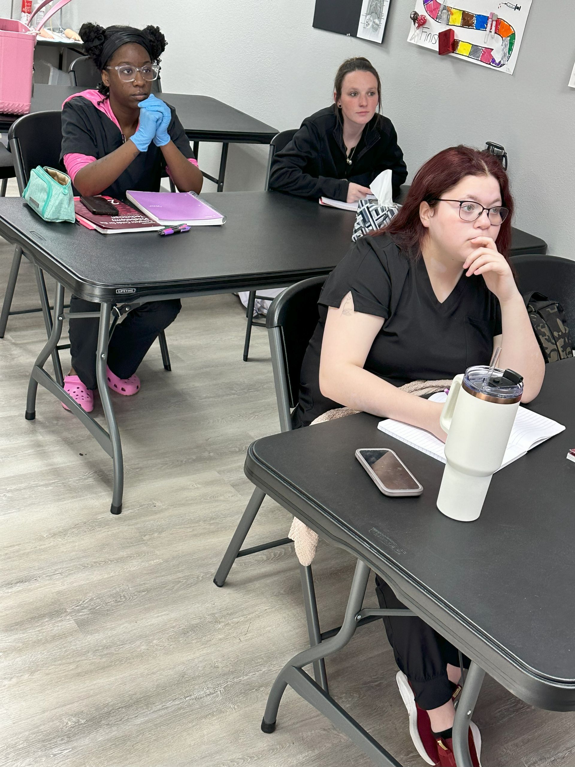 A group of women are sitting at tables in a classroom.