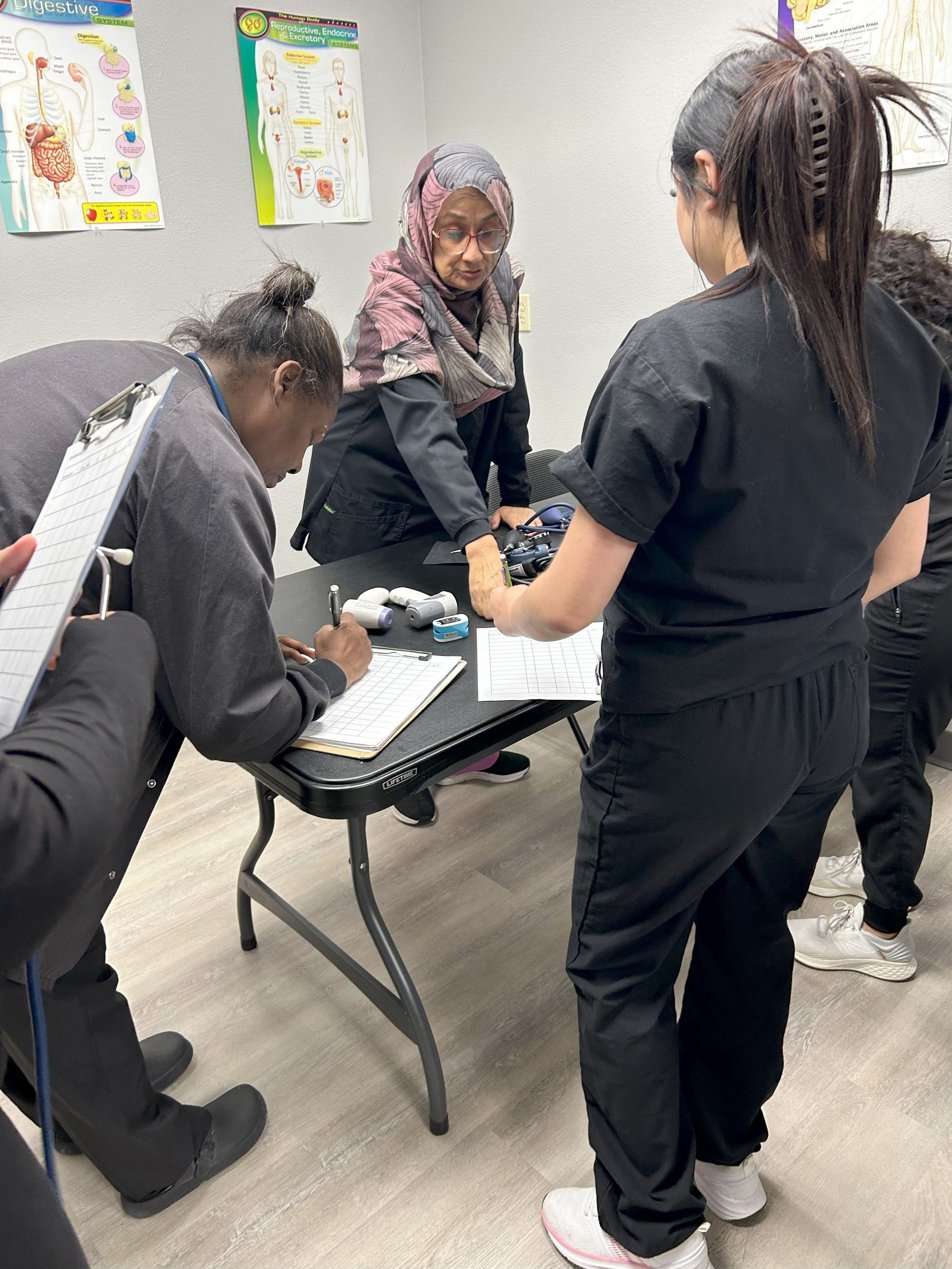 A nurse practicing on a simulated patient's arm in a classroom.