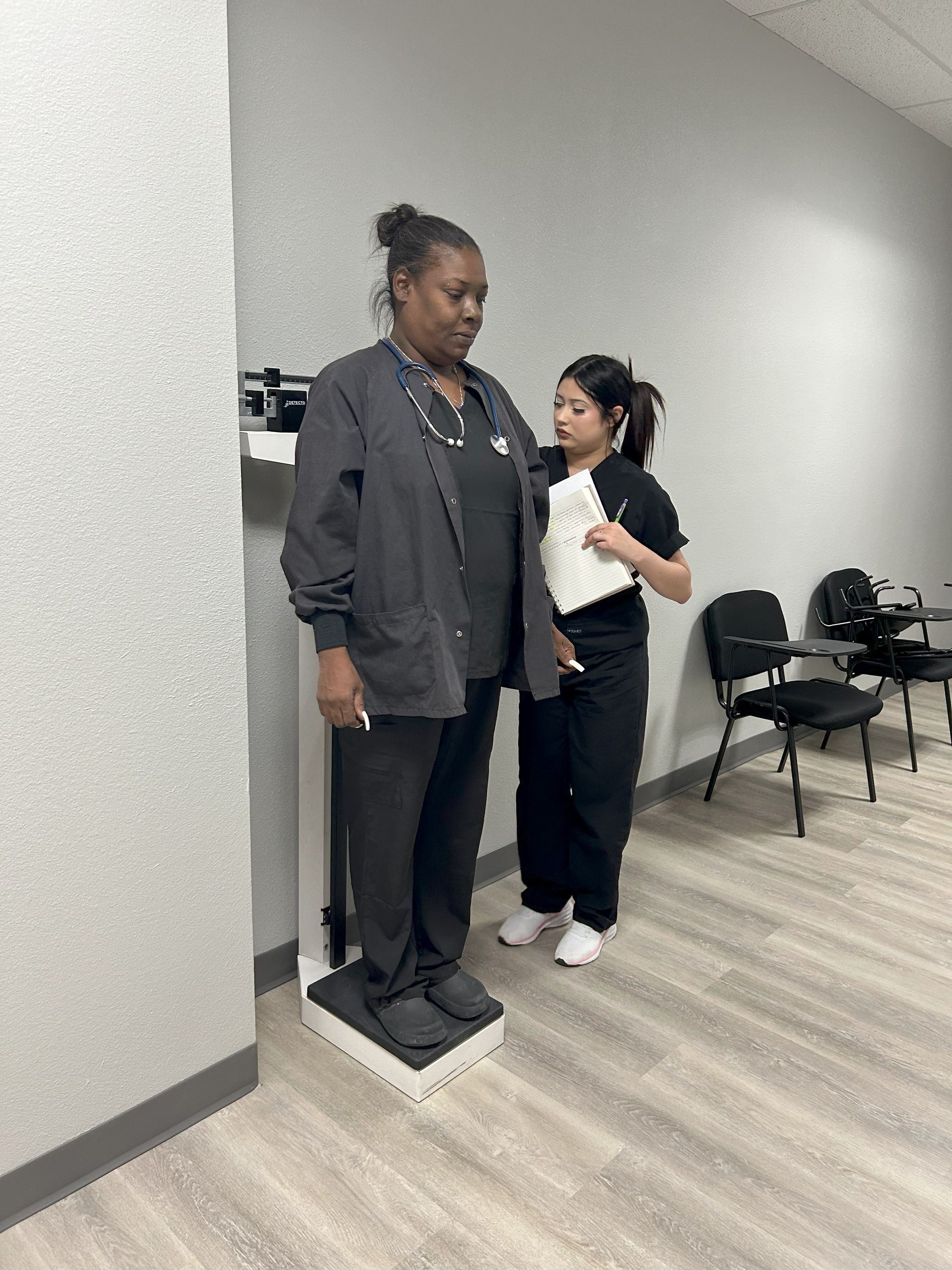 Two nurses are working on a patient's arm in a classroom.