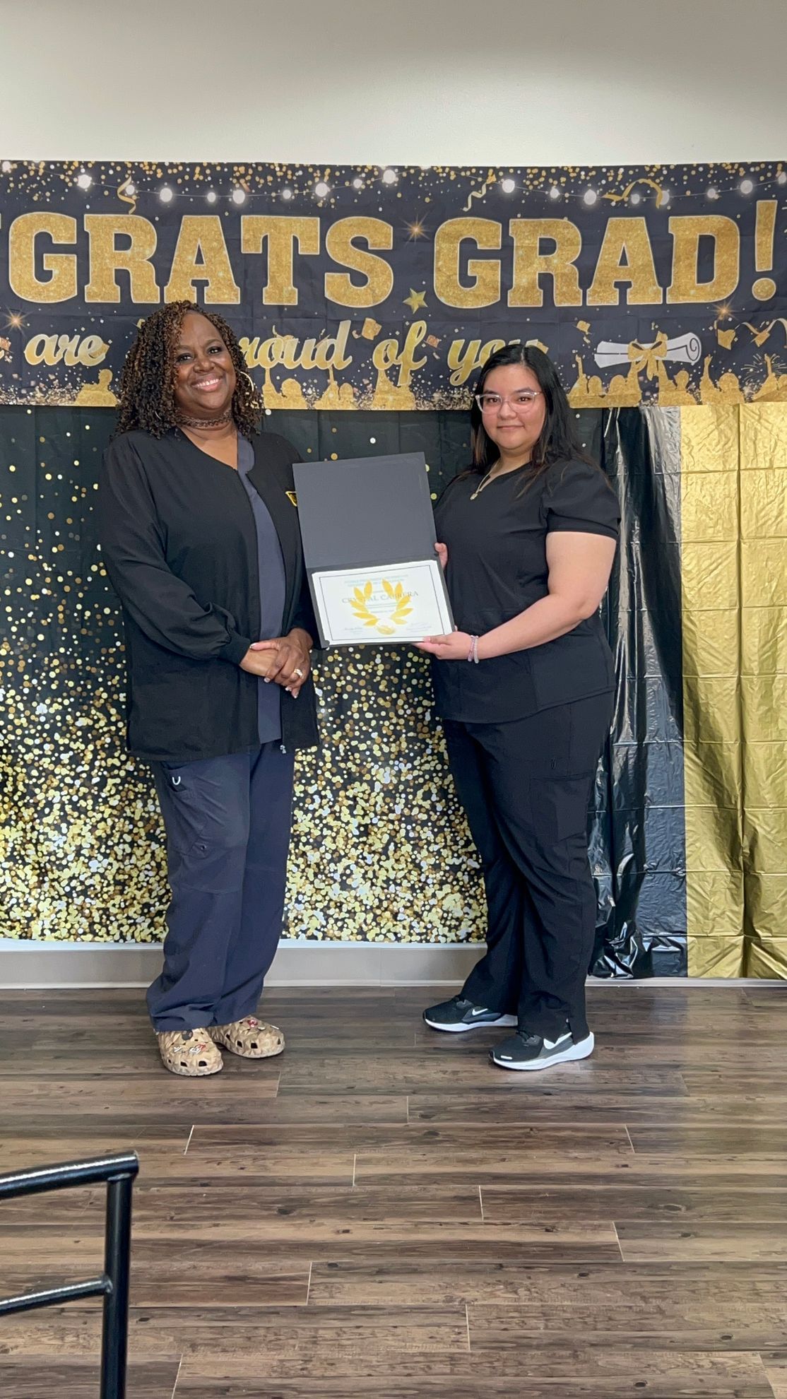 Two women are standing next to each other holding a certificate.