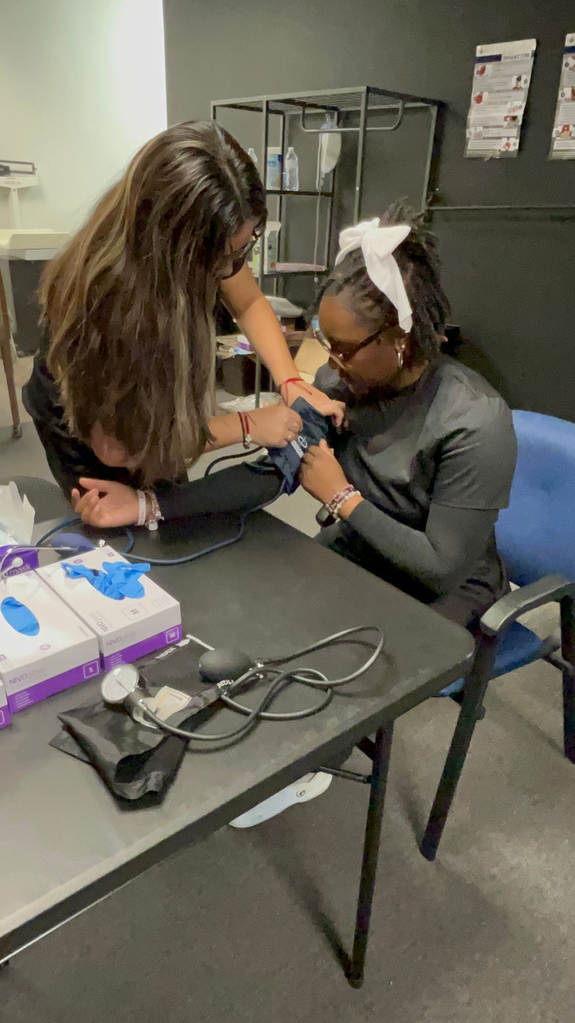 Two nurses are working on a patient's arm in a classroom.