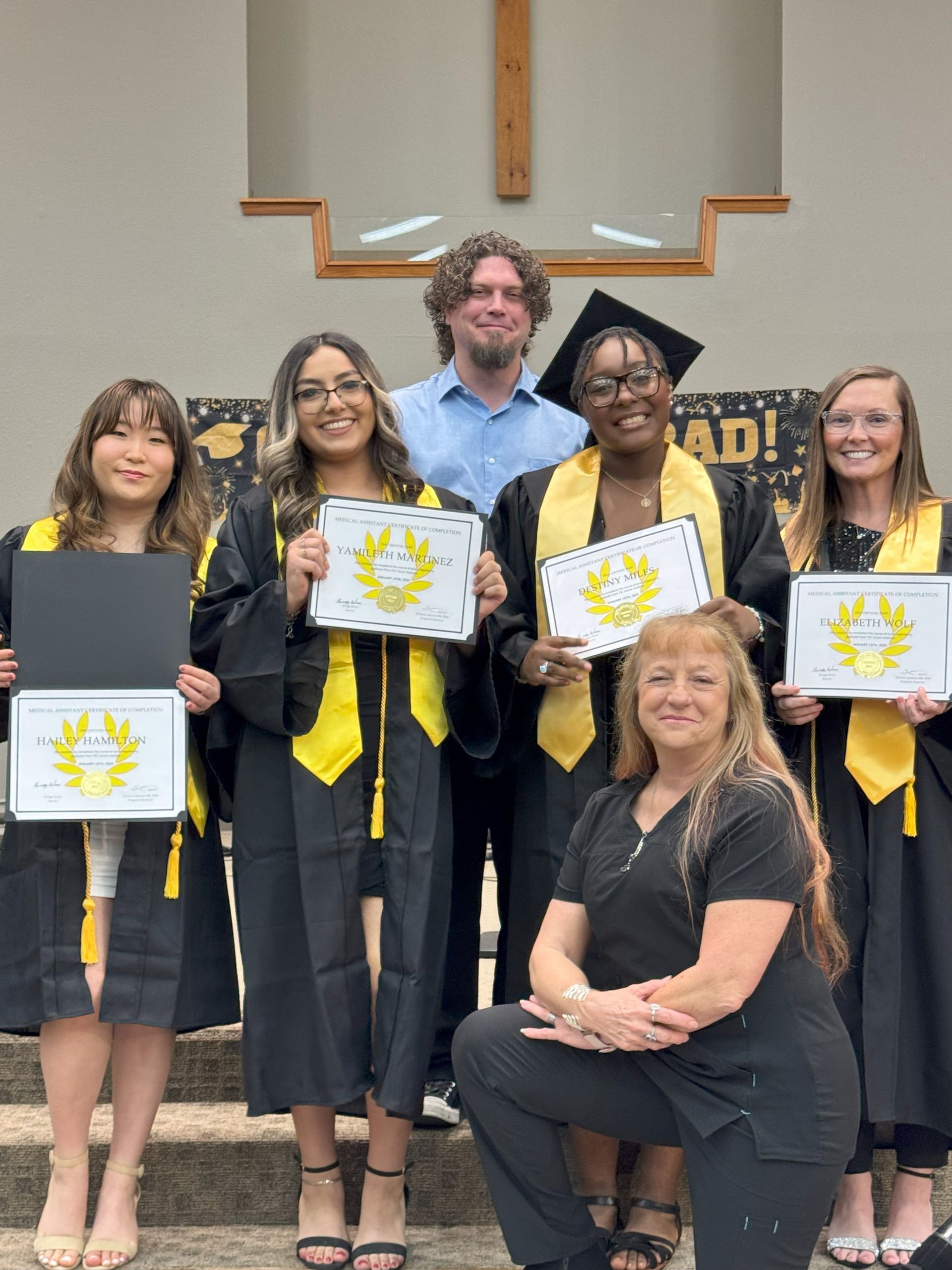 A group of graduates are posing for a picture while holding their diplomas.