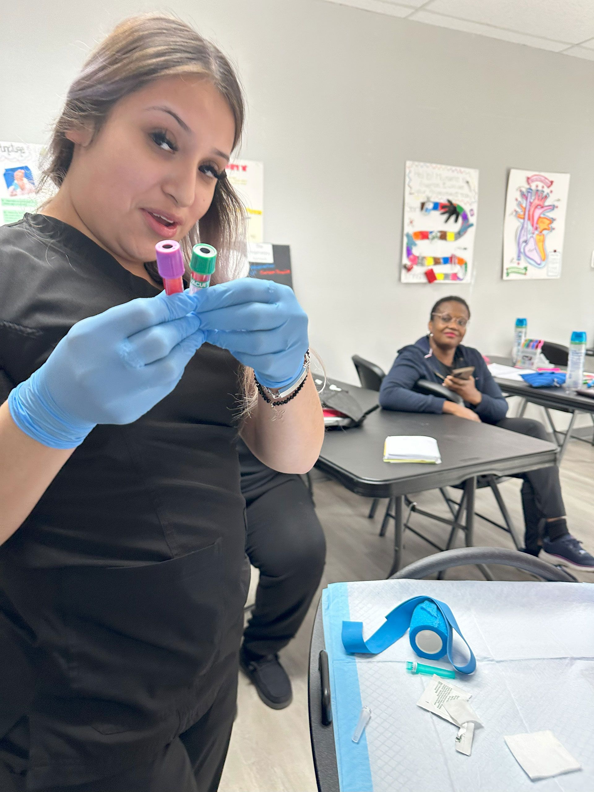 A woman wearing blue gloves is holding two blood collection tubes