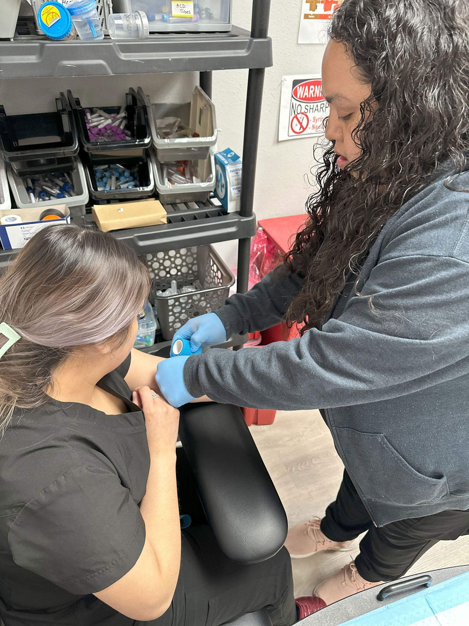 A woman applying bandage to an arm